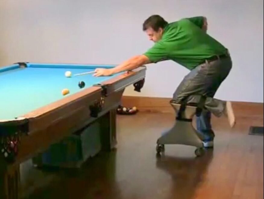Man using RollerFoot hands-free knee scooter while playing billiards